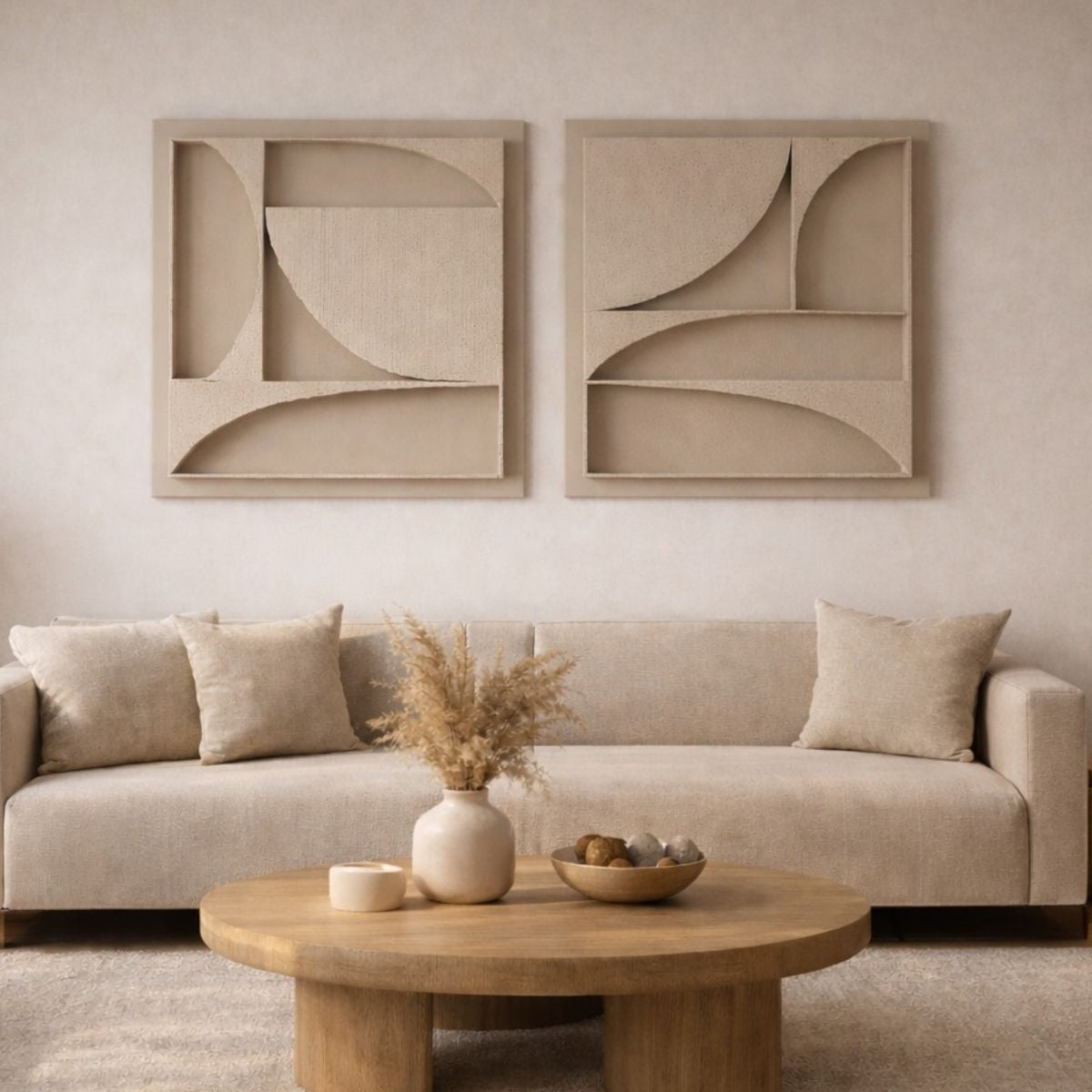 The Karma Series, a set of two handmade 3D structural wall art pieces, hung on a wall in a luxurious Nordic style living room above a luxurious beige couch. There is an elegant wooden coffee table standing in front of the sofa with calming designer objects as decoration standing on top of it.