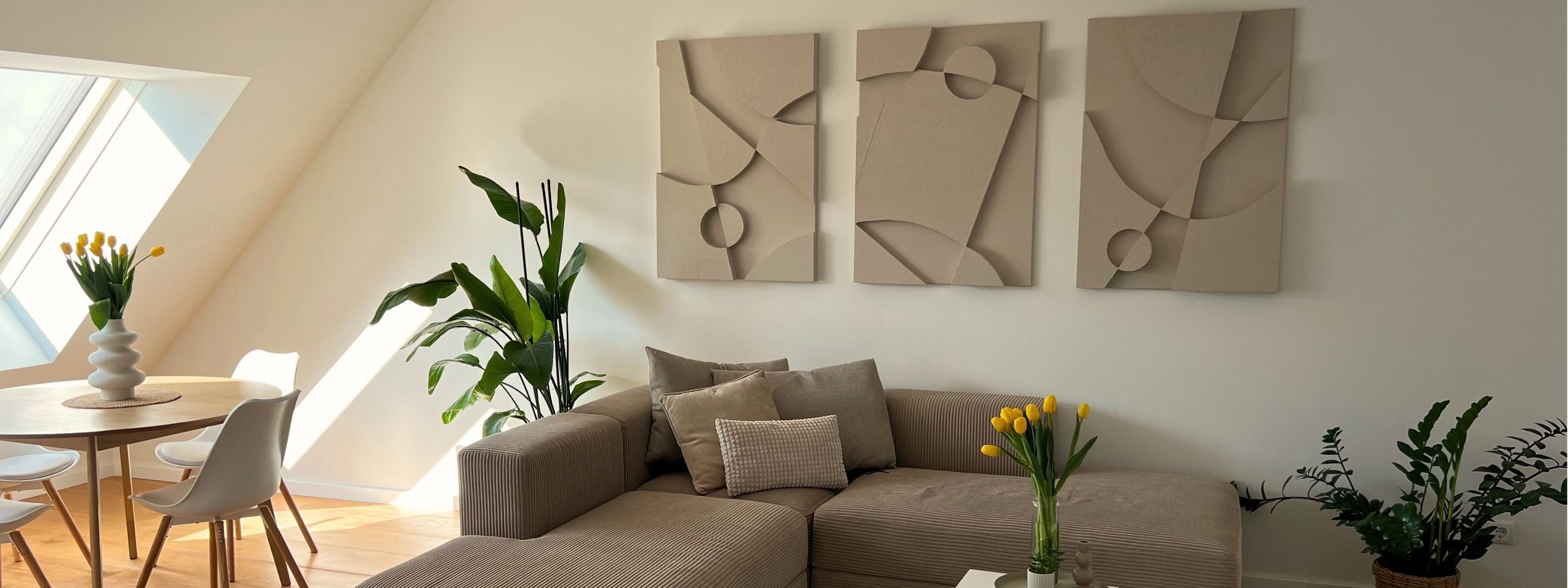 Modern living room with a modern beige sofa. The Warrior Series, a set of three 3D abstract wall art pieces hung above the couch. Decorative plants elegantly placed across the room.